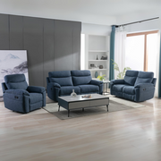A modern living room featuring the Vera Recliner Sofa in blue, a rectangular coffee table, large window with sheer curtains, light wood flooring, and minimalist decor with plants and artwork offers stylish comfort.