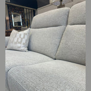 Close-up of the Luna Electric Recliner in light gray, featuring a patterned white pillow on the left side, set in a stylish living room with a lamp and decor visible in the background.