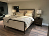 The Hampshire Bedframe, featuring dark wood and luxurious upholstery, is enhanced by a side lamp, bringing elegance to your bedroom.