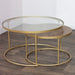 The Andree Coffee Table set includes two modern nesting tables—one with a round glass top, the other slightly smaller with a wooden top—both accented by elegant brass legs and designed to complement any wooden floor.