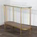The Andrea Console Table boasts an elegant gold metal frame, oval glass top, and wooden lower shelf with a herringbone pattern—ideal for placement against a white wall on dark wood floors.