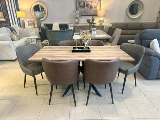 The Elson Table & 6 Diamond Chairs - Special Offer features four gray fabric and two brown leather chairs, elegantly displayed in a showroom with sofas, mirrors, lamps, and décor in the background.