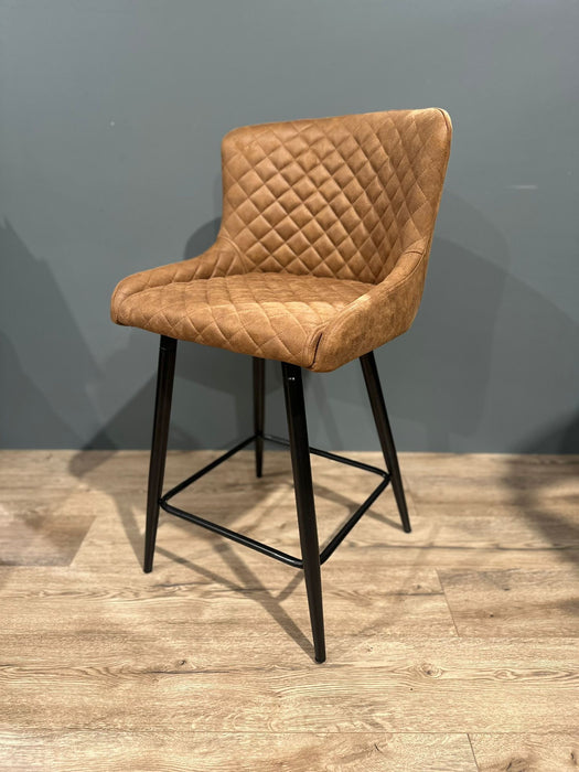 The Diamond Barstool features brown PU leather with quilted diamond stitching, a low backrest, and black metal legs—an ideal addition to any kitchen island.