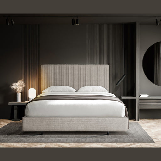 A modern minimalist bedroom featuring the Valerie Bedframe, white bedding, a dark accent wall, round mirror, bedside table with lamp and dried pampas grass, all atop wood flooring in a striking herringbone pattern.