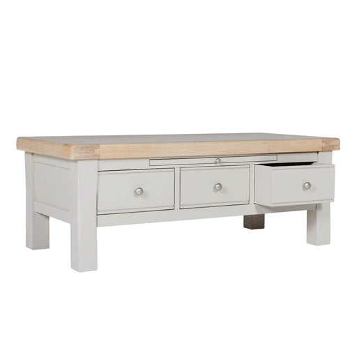 Rectangular table with a natural wood top and a painted gray base featuring three storage drawers, one of which is open.