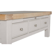 A close-up of the Doune Coffee Table, featuring a light gray finish, natural oak veneer top, three storage drawers with silver knobs.
