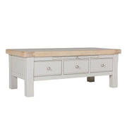 A taupe coffee table with oak veneer top, featuring three small drawers with metal handles.