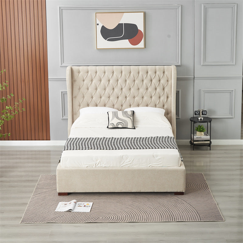 A modern bedroom featuring the Vienna Bedframe with a beige tufted winged headboard, white and gray bedding, a side table with a clock and plant, abstract wall art, and a gray patterned rug on light wood flooring.