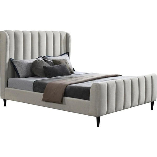 The Isobella Bedframe is a modern upholstered bed featuring a high headboard with vertical channel tufting in soft stone linen, styled with grey and black bedding, multiple pillows, and a folded brown blanket at the foot.