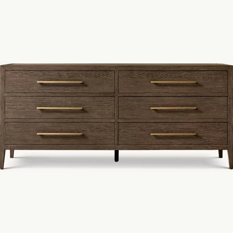 The Hampshire Wide Chest is a modern wooden dresser with a dark wood finish, six drawers featuring long slim gold handles, and short angled legs, perfect for adding style and storage to your bedroom.