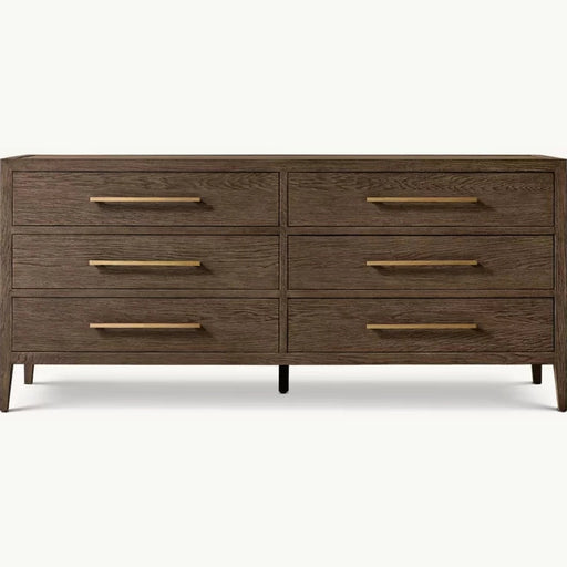 The Hampshire Wide Chest is a modern wooden dresser with a dark wood finish, six drawers featuring long slim gold handles, and short angled legs, perfect for adding style and storage to your bedroom.