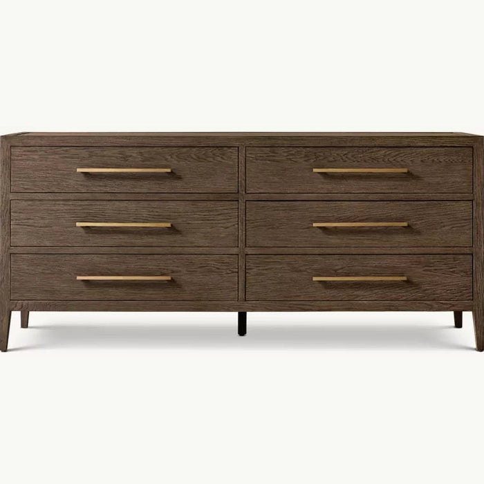 The Hampshire Wide Chest is a modern wooden dresser with a dark wood finish, six drawers featuring long slim gold handles, and short angled legs, perfect for adding style and storage to your bedroom.