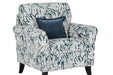 The Pippa Accent Chair features dark wooden legs and white fabric with dark blue abstract leaf designs. It comes with a matching dark blue square cushion for added comfort.