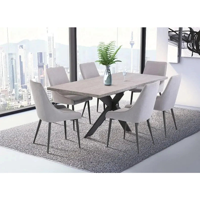 A modern dining room features a Rimini Dining Table in stone melamine, six light gray chairs, a vase with green fern leaves, and a gray rug. Large windows frame a stunning city skyline in the background.