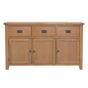 The Saoirse Large Sideboard is a premium wooden piece with three top drawers, three lower cabinet doors, black metal handles, and a natural solid oak finish. Handmade and classic in design, it brings both style and function to your space.
