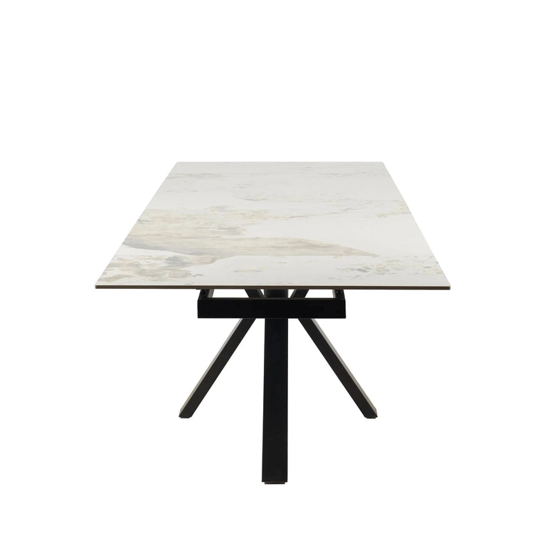 The Sorrento Dining Table features a modern design with a light marble-style top and black metal legs arranged in a central, angled base, shown from the short end facing the viewer.