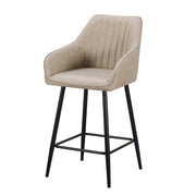 The Enzo Counter Stool features a modern design with a light beige upholstered seat and backrest with vertical stitching, armrests, and four slim black metal legs with a footrest.